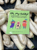 A copy of the green cover "Oh, My Gulay" coloring book is displayed on top of white daikon radishes at a supermarket